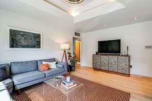 A modern living room with a sofa, a coffee table, a television, and a patterned cabinet. - Casa de Plazaola! Mid-Century Oasis Near ASU (Tempe)