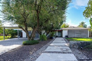 A residential property with a paved driveway, a covered patio, and a garage. - Casa de Plazaola! Mid-Century Oasis Near ASU (Tempe)