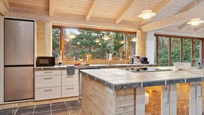Una cocina moderna con una isla grande, electrodomésticos de acero inoxidable y ventanas amplias que ofrecen vistas al exterior.