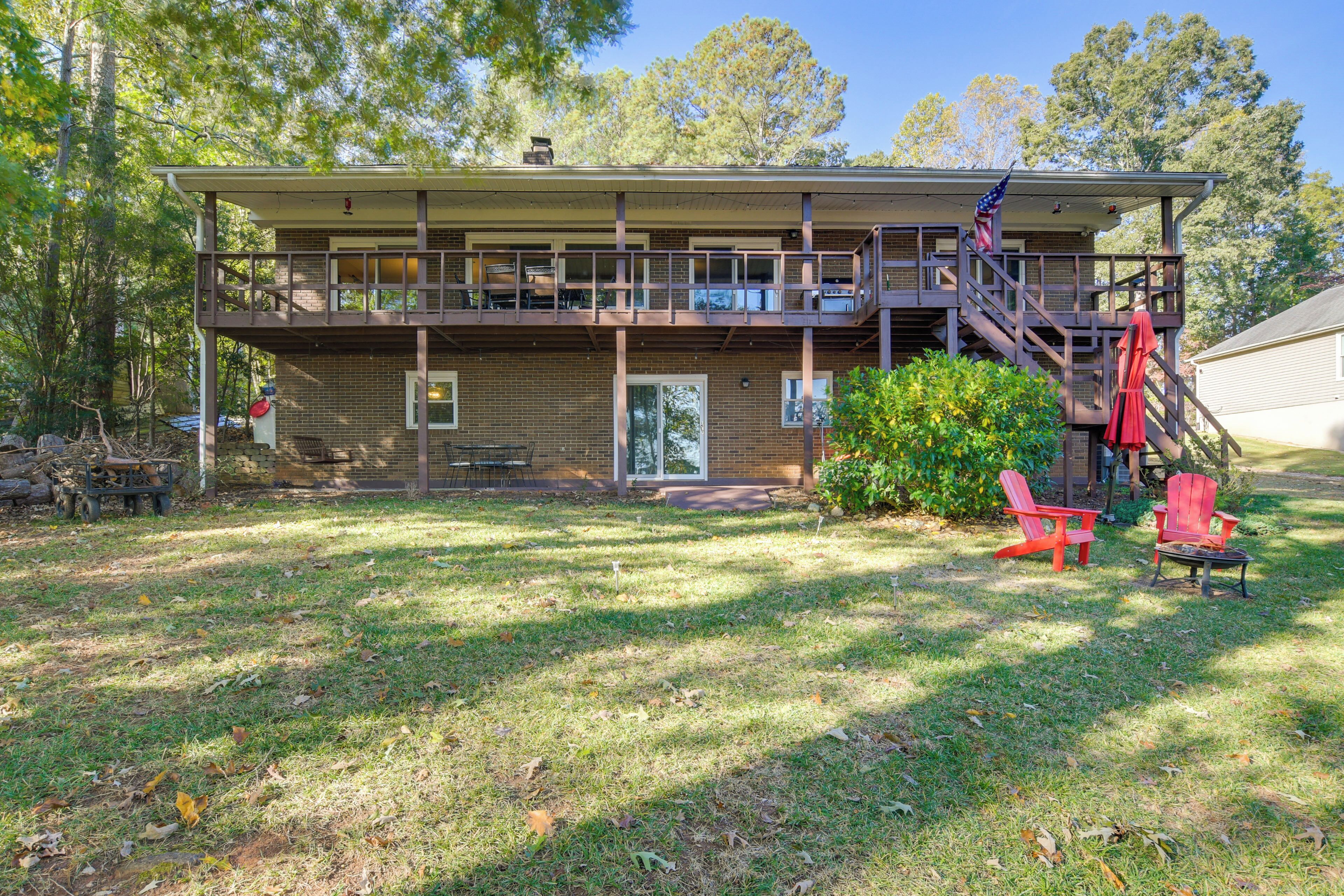A two-story house with a balcony, a staircase, and a front yard with chairs.