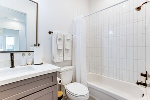 A modern bathroom with a white sink, toilet, and bathtub. - Your Houston HQ! Modern Unit w/ Yard & Workspace (Houston)