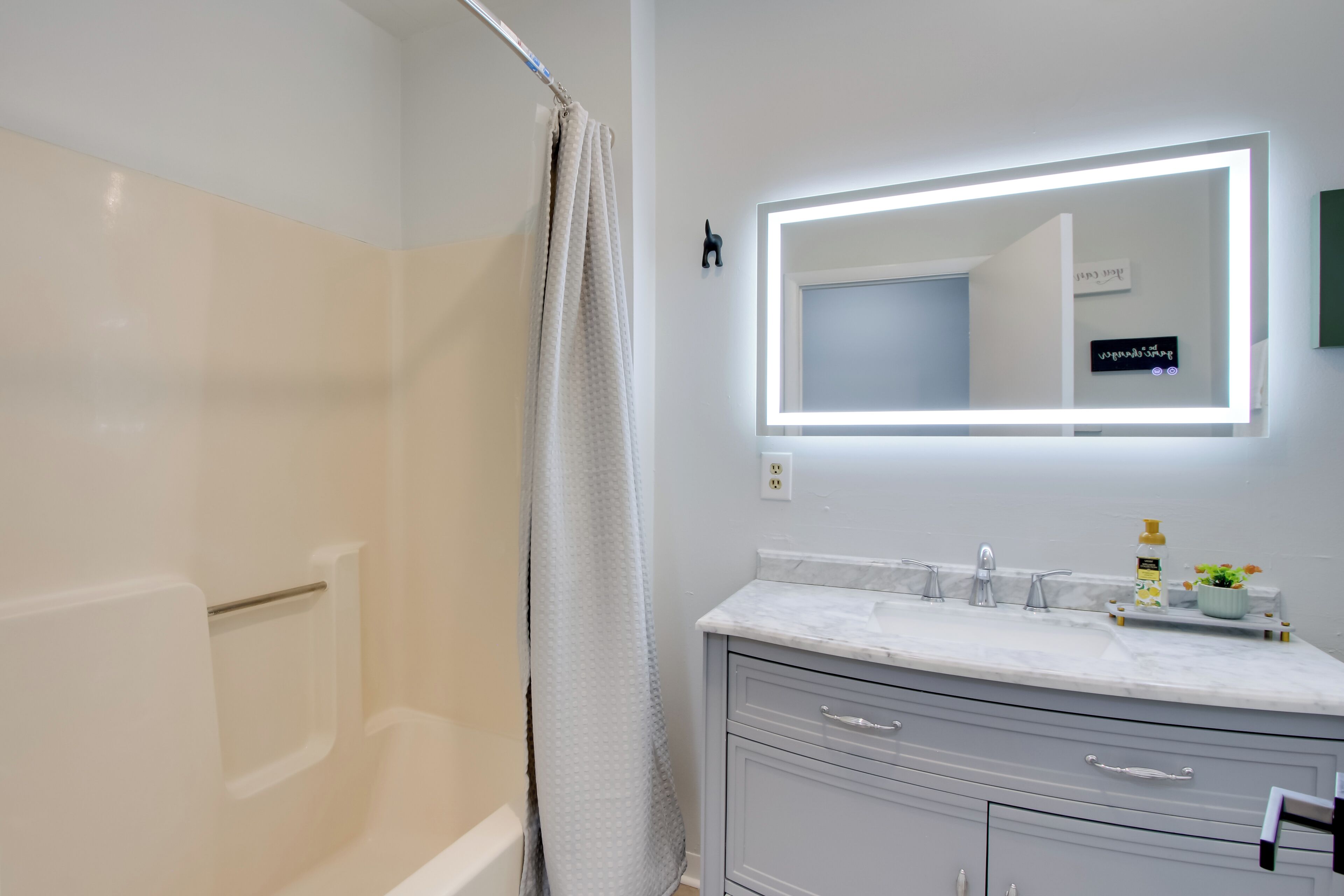 A modern bathroom with a shower, a vanity with a mirror, and a towel rack.