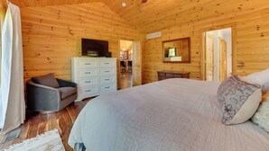 A wooden cabin bedroom with a bed, a dresser, a television, and a ceiling fan. - Luxury Cabin in The Reserve at Boyne Mountain (Boyne City)
