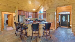 A spacious kitchen with a central island, wooden cabinets, and a stone-tiled floor. - Luxury Cabin in The Reserve at Boyne Mountain (Boyne City)