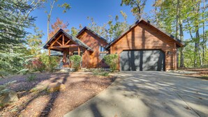 A log cabin with a garage, surrounded by trees and a well-maintained garden. - Luxury Cabin in The Reserve at Boyne Mountain (Boyne City)