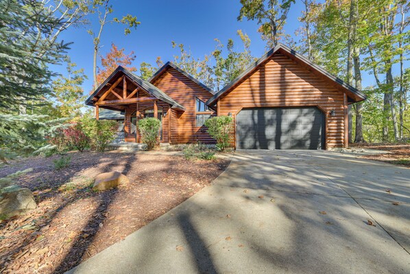 Eine Blockhütte mit Garage, umgeben von Bäumen und einem gepflegten Garten.