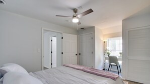 Un dormitorio con cama, ventilador de techo y escritorio con silla.