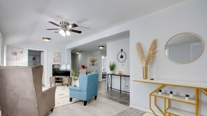 Una sala de estar moderna con un sillón beige, un sofá azul y una consola blanca con estantes.