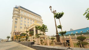 A grand hotel with a classical facade, a prominent dome, and a well-maintained garden with pathways and lamp posts. - Maharaja Palaces Rohtak (Sampla)
