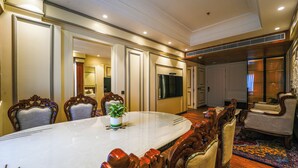 A conference room with a large table, ornate chairs, a potted plant, and a television. - Maharaja Palaces Rohtak (Sampla)