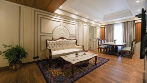 A living room with a sofa, coffee table, and dining area with chairs. - Maharaja Palaces Rohtak (Sampla)