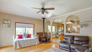 A spacious living room with a fireplace, a leather sofa, and a dining area with a table and chairs. - 3 Mi to Sequoia Park Zoo: Spacious Home w/ Sunroom (Eureka)