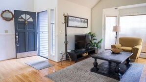 Un salon avec un téléviseur, un canapé, une table basse et une porte.