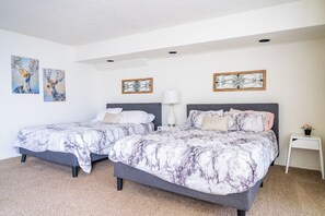 Un dormitorio con dos camas, una lámpara blanca y dos obras de arte en la pared.