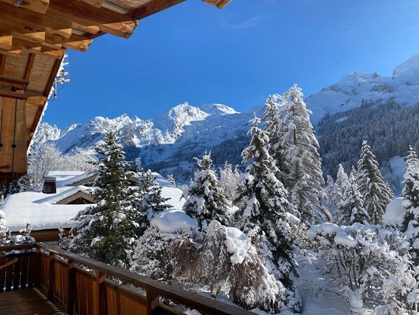 A wooden deck overlooking a snowy mountain landscape with a clear blue sky.