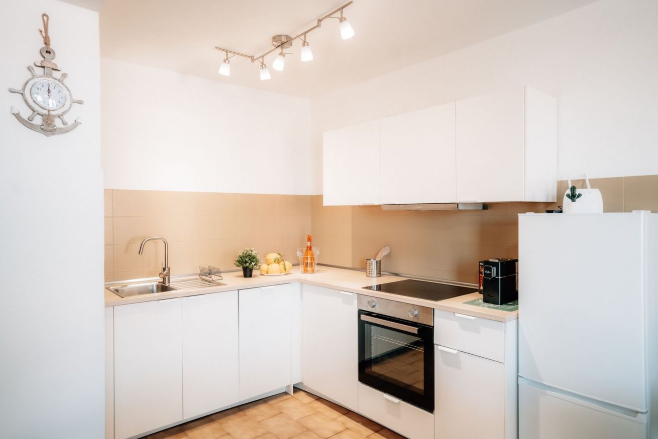 Een keuken met witte kastjes, een spoelbak, een fornuis en een koelkast.