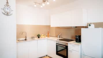 Een keuken met witte kastjes, een spoelbak, een fornuis en een koelkast.