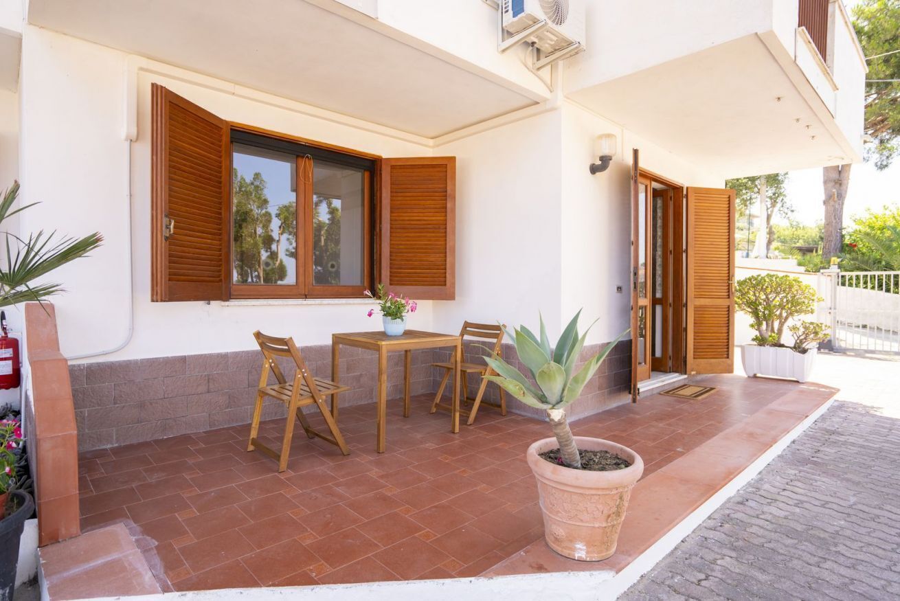 Una terrazza con tavolo e sedie, una pianta in vaso e un estintore.