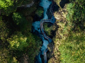 Luchtbeeld van een rivier met een houten brug en omliggend groen.