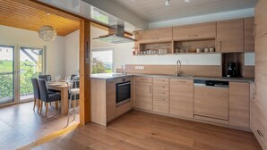 A modern kitchen with wooden cabinets, a built-in oven, and a dishwasher. - Apartment 'Agnes' with Shared Pool, Private Terrace and Wi-Fi (Rheinfelden)