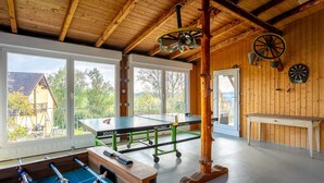 A wooden room with a ping pong table, foosball table, and a dartboard. - Apartment 'Agnes' with Shared Pool, Private Terrace and Wi-Fi (Rheinfelden)
