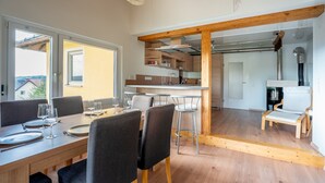A modern dining area with a wooden table and chairs, a kitchen in the background, and a view through an open door. - Apartment 'Agnes' with Shared Pool, Private Terrace and Wi-Fi (Rheinfelden)