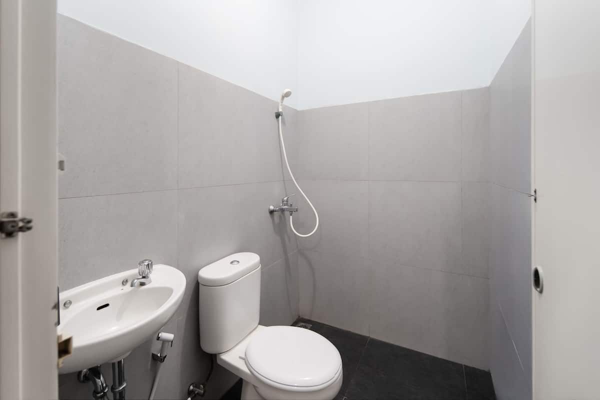 Une petite salle de bain moderne avec un lavabo, des toilettes et une douche, le tout de couleur blanche.