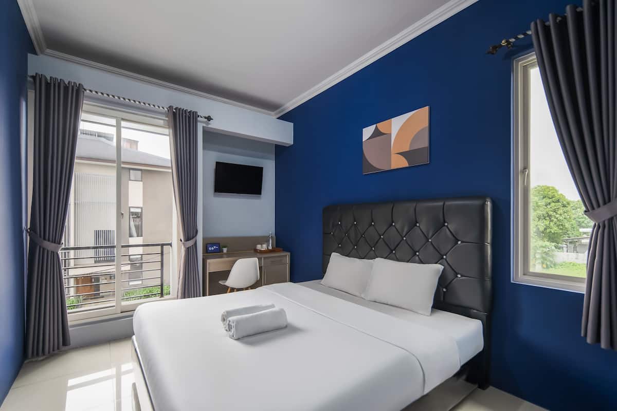 Une chambre d’hôtel comprenant un lit, un bureau, une chaise, une télévision et un balcon.