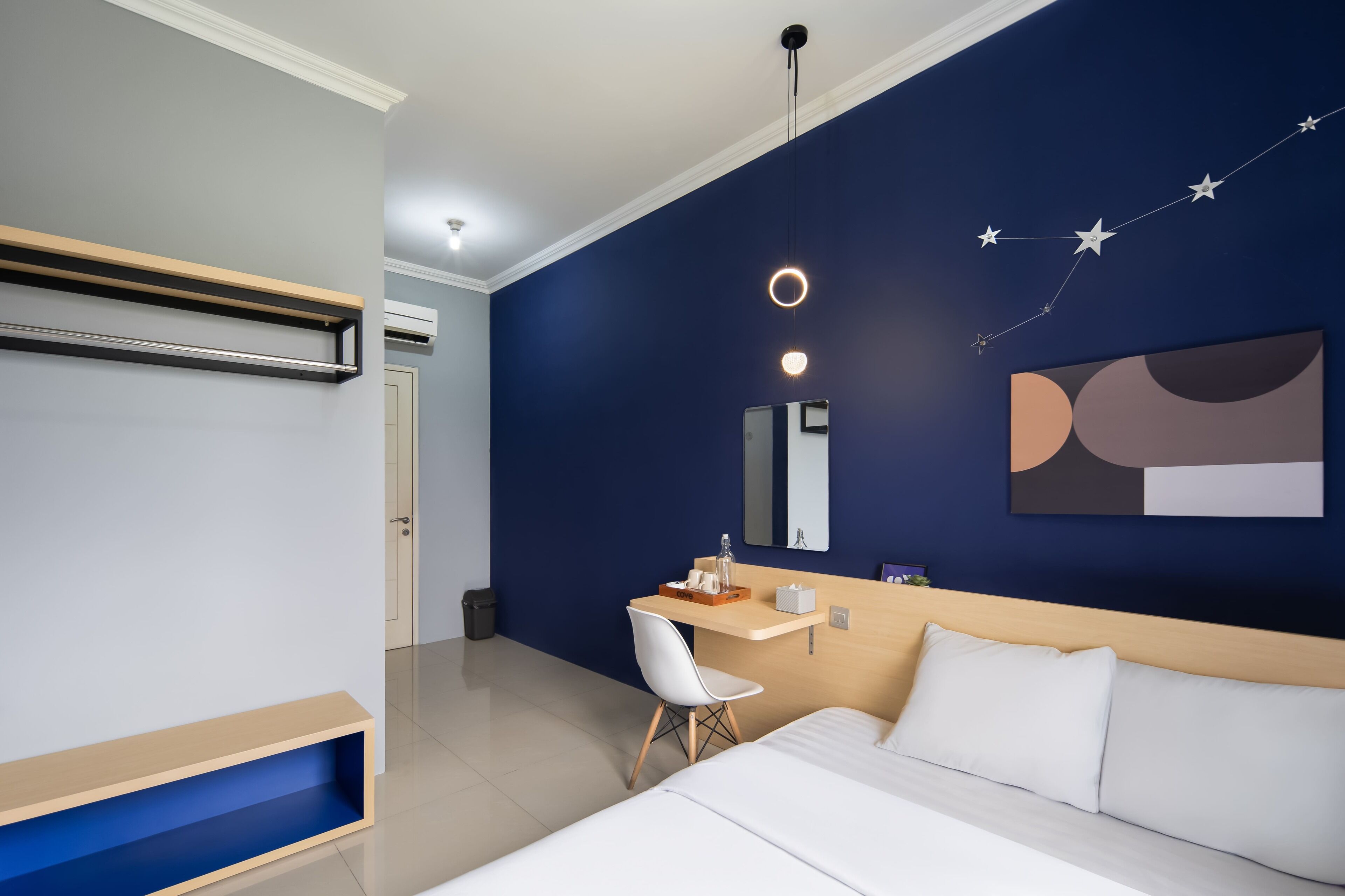 Una habitación de hotel moderna con cama, escritorio, silla y mesita de noche.