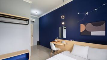 Una habitación de hotel moderna con cama, escritorio, silla y mesita de noche.
