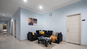 Un soggiorno moderno con un divano nero, un tavolino in vetro e una porta beige.