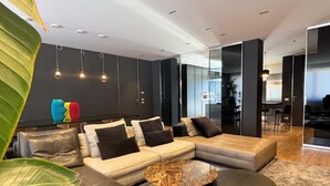 A modern living room with a sectional sofa, a round coffee table, and a large plant. - Exclusive penthouse with panoramic terrace and private pool in the center of Alba (ALBA)