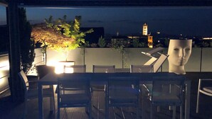 A rooftop terrace with a pool, dining area, and a view of a cityscape including a tower. - Exclusive penthouse with panoramic terrace and private pool in the center of Alba (ALBA)