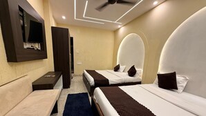 Une chambre d’hôtel moderne équipée de deux lits, d’un bureau, d’une télévision et d’un ventilateur de plafond.