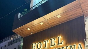 Une enseigne d’hôtel portant le nom « Hotel Radha Krishna » est illuminée.