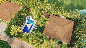 Eine Luftaufnahme eines Resorts mit mehreren Gebäuden, einem Schwimmbecken und üppigen Palmen.