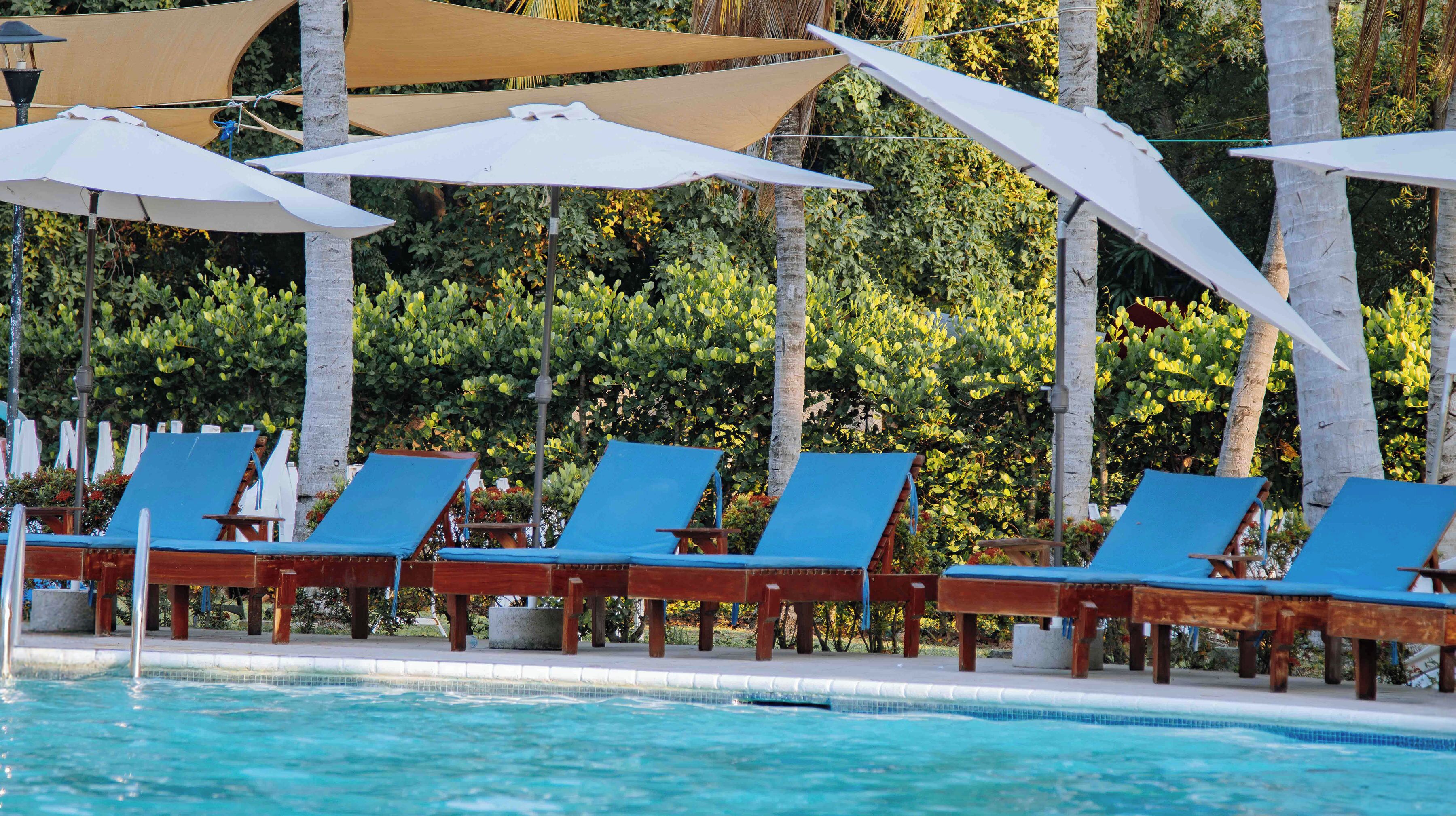 A poolside area with lounge chairs and umbrellas.