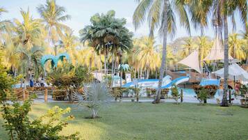A resort with a pool area, palm trees, and a water slide.