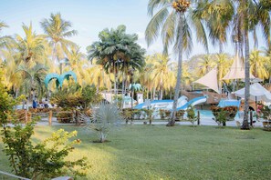 Ein Resort mit Poolbereich, Palmen und einer Wasserrutsche.
