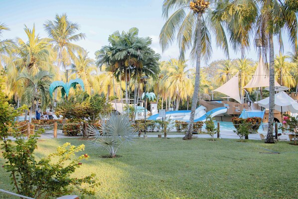 Un resort con piscina, palmeras y un tobogán de agua.