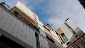 Un edificio moderno con techo plano, ventanas grandes y un balcón con plantas.