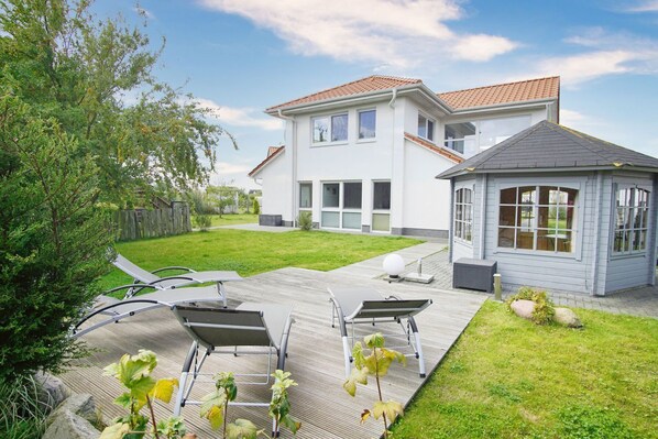 A modern two-story house with a patio area featuring outdoor furniture.