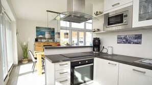 A modern kitchen with white cabinets, a built-in oven, a microwave, and a coffee maker. - Villa Kristall - house in an idyllic location with conservatory, terrace and garden (Trent)