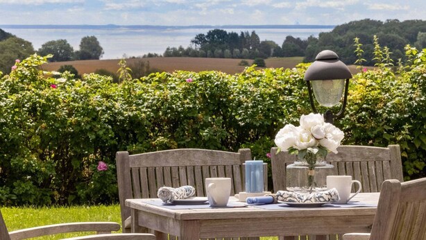 A wooden table set outdoors with a view of a lake and greenery in the background.