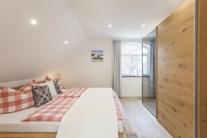 Ein Schlafzimmer mit einem Bett, Kissen, einem Fenster und einer Holzwand.