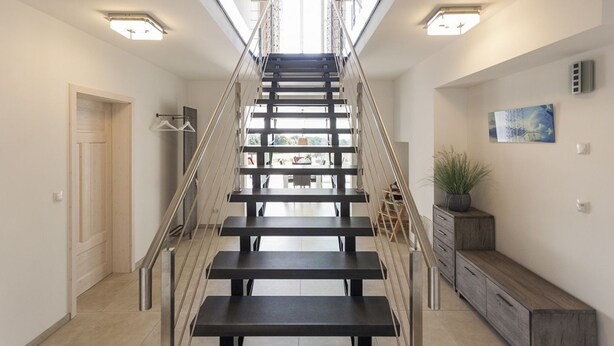 Una escalera moderna con barandilla de metal que lleva a un piso superior.