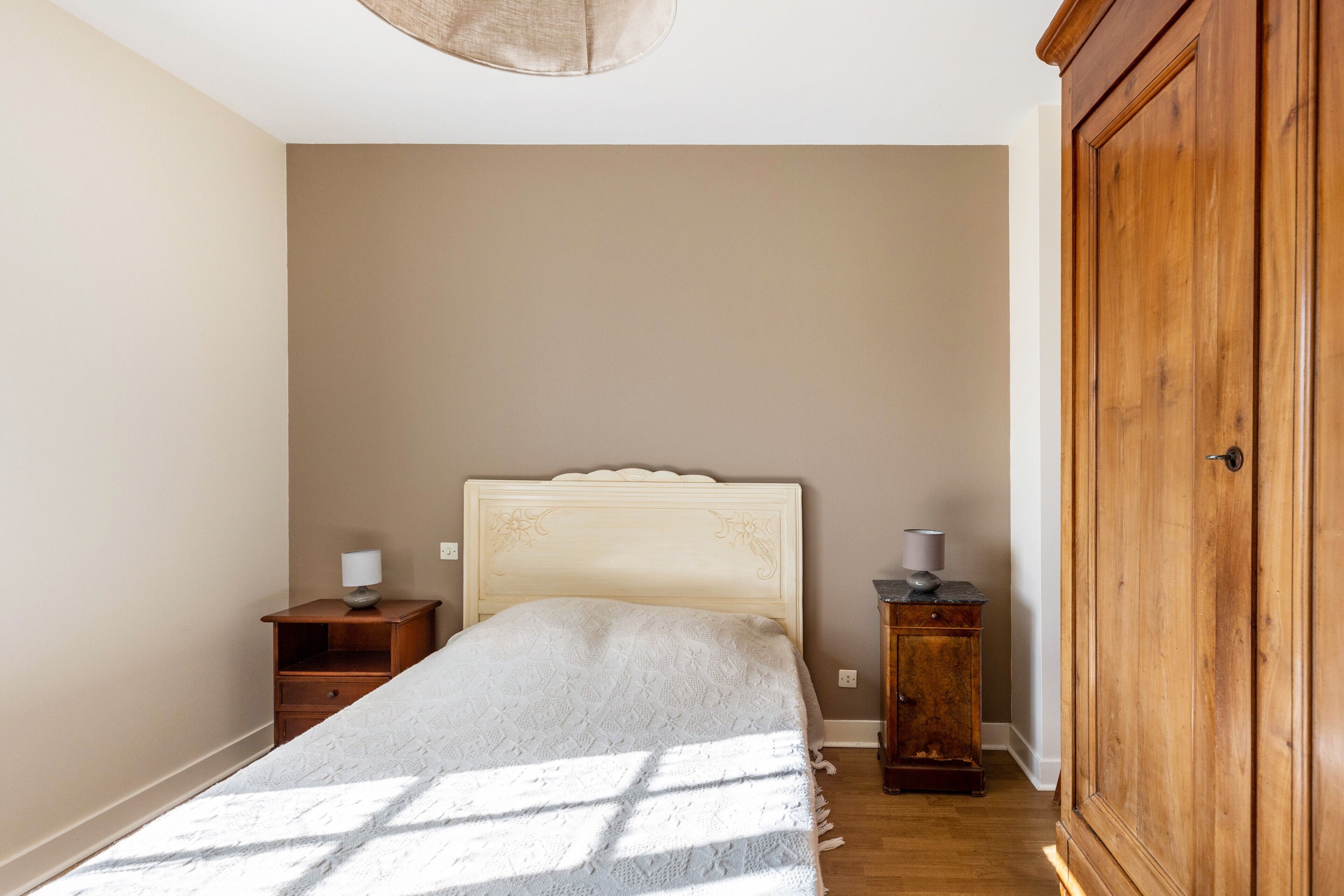 A bedroom with a bed, a nightstand, a dresser, and a wardrobe.