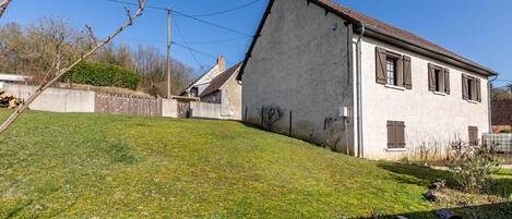 A single-story house with a sloped roof, a small front yard, and a wooden fence.