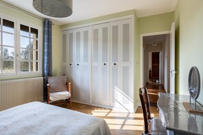 A bedroom with a bed, a chair, a table with a mirror, and a set of white louvered closets. - Pavilion in the Loir Valley (Saint-Rimay)