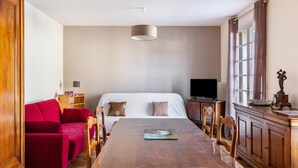 A room with a bed, a red sofa, a wooden dining table, and a television. - Pavilion in the Loir Valley (Saint-Rimay)
